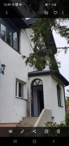 Biały dom z czarnymi drzwiami i schodami w obiekcie Millanova w mieście Milanówek