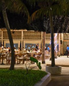 a group of people sitting at tables in a restaurant at NDAME Paje Hotel in Paje