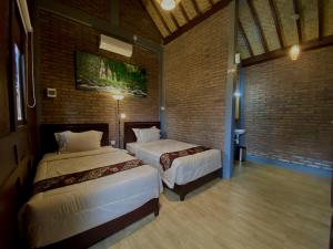 Licin的住宿－Kayon Griya Osing Villa - Ijen，一间卧室设有两张床和砖墙