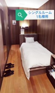 1 dormitorio con cama y zapatos en el suelo en Petit Hotel mio en Saitama