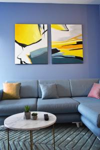 a living room with a blue couch and two paintings at Vibrant Apartment in Tirana