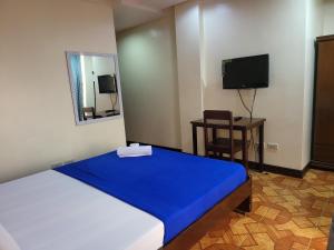een slaapkamer met een groot bed en een blauwe deken bij Rooms R Us - Voyagers Palace in Puerto Princesa City