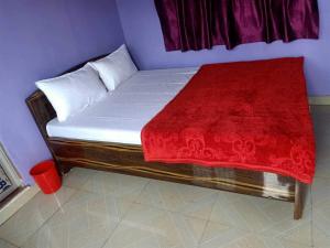 a bed in a room with a red blanket on it at Hotel Priyal Inn in Bokāro