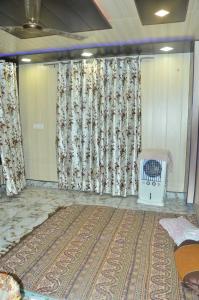 een kamer met een groot tapijt en gordijnen en een wieg bij POP Sneha Homestay in Dhār Khurd