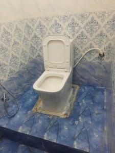 een toilet in een badkamer met een blauwe betegelde muur bij SPOT ON Sana Guest House in Lucknow