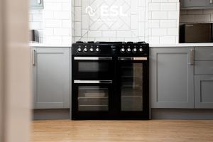 a black oven in a kitchen with white cabinets at Sunnyside, Henblas Road, Wrexham 