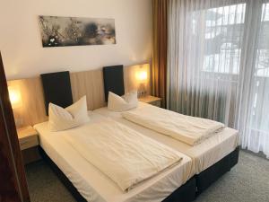 a bedroom with a bed with white sheets and a window at Chiemgau Appartements in Inzell