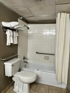 a bathroom with a white toilet and a bath tub at Devils Lake Inn in Devils Lake