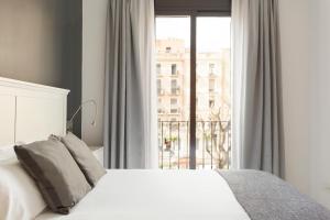 a bedroom with a white bed and a window at Andreas Apartments in Tarragona