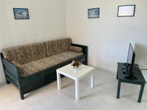 ein Wohnzimmer mit einem Sofa und einem Tisch mit einem TV in der Unterkunft Angelos Furnished Apartments in Amoopi