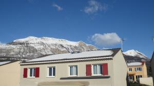 a house with red doors and a mountain in the background at Loue Chambre ds mon appartement ou je vis in Gap