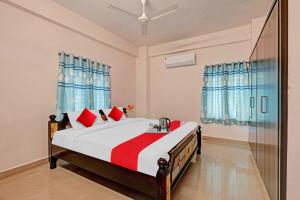 - une chambre avec un lit et des oreillers rouges dans l'établissement OYO Coastal Inn Luxury Service Apartments, à Kakinada
