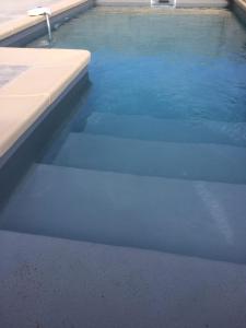 een groot zwembad met blauw water en avisor bij La Grange de Papy in Vallon-Pont-dʼArc