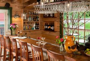 a bar with a table with chairs and a vase of flowers at Squam Lake Inn in Holderness