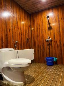 a bathroom with a toilet and a wooden wall at Royal Tree Cafe And Resort in Dehradun