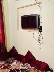 Habitación con TV en la pared y cama en POP Misba Homestay, en Bhadarwāh