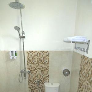 uma casa de banho com um chuveiro e um WC. em Kayon Griya Osing Villa - Ijen em Licin