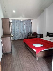 a bedroom with a large bed with a red blanket at SPOT ON Hotel Rudra in Kulu