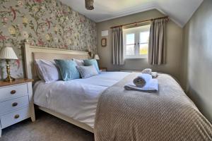 ein Schlafzimmer mit einem Bett und einem Fenster in der Unterkunft Martie Cottage - cosy cottage idyllic village in Whitcombe