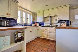 eine Küche mit weißen Schränken und einem Fliesenboden in der Unterkunft Martie Cottage - cosy cottage idyllic village in Whitcombe + 16 Fotos