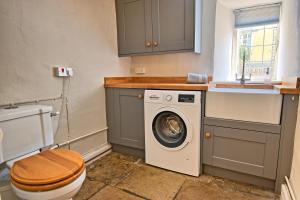 a bathroom with a washing machine and a toilet at Martie Cottage - cosy cottage idyllic village 