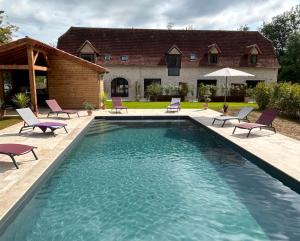 a swimming pool with chairs and a house at Les Noyers De Gaudelle in Saint-Sozy