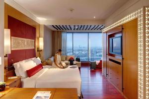 ذا اتش دبي في دبي: رجل يجلس على سرير في غرفة فندق