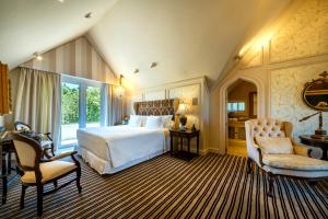 a bedroom with a large white bed and a chair at Castelo Saint Andrews in Gramado