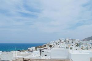 a view of a town with white buildings and the ocean at Castlevania- Traditional house in the Castle in Naxos Chora