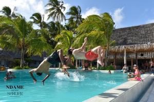 two people jumping in the water in a swimming pool at NDAME Paje Hotel in Paje