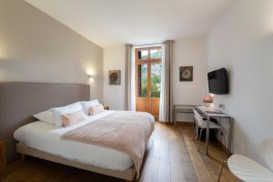Schlafzimmer mit einem Bett, einem TV und einem Fenster in der Unterkunft Le Manoir d'Agnès Logis hôtel restaurant in Tarascon-sur-Ariège
