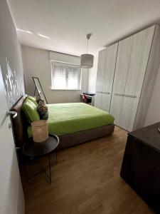 Un dormitorio con una cama verde y una silla en Appartamento Cactus, en Montanara