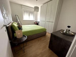 Un dormitorio con una cama verde y una mesa en Appartamento Cactus, en Montanara