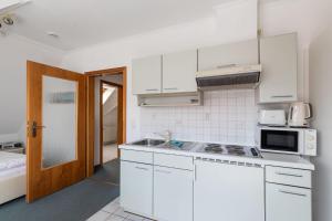 uma cozinha branca com um lavatório e um micro-ondas em Fischerhus, Whg 9 em Duhnen