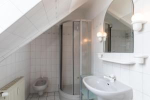 uma casa de banho branca com um lavatório e um WC em Fischerhus, Whg 9 em Duhnen
