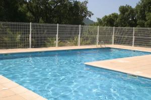 uma piscina com água azul em frente a uma cerca em Villa 3 chambres vue mer Valcros em La Londe-les-Maures