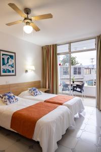 a bedroom with two beds and a large window at Apartamentos Maspalomas Foresta in Maspalomas