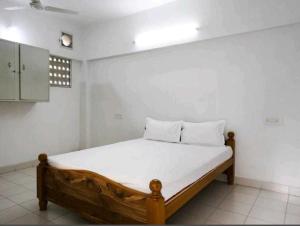 1 dormitorio con cama de madera en una habitación blanca en SPOT ON Shappy Inn Koyambedu Near PVR SPI Palazzo Chennai, en Chennai