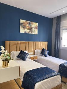 two beds in a room with blue walls at HOSTAL MH BORJ in Martil