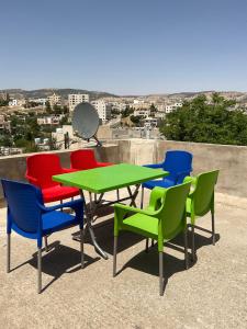un gruppo di sedie colorate e un tavolo sul tetto di Black IRIS a Jerash