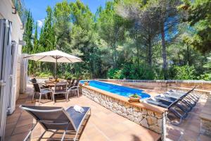 eine Terrasse mit einem Pool, Stühlen und einem Sonnenschirm in der Unterkunft Bonaire in Cielo de Bonaire 
