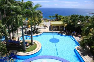 an overhead view of a pool with palm trees and the ocean at Hotel Olé Caribe in Macuto