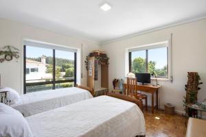 een slaapkamer met 2 bedden, een bureau en ramen bij Sobreiro22 in Lourosa