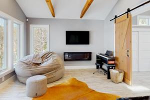 uma sala de estar com uma cama, uma televisão e um piano em Grove Road Lakehouse em Barnard