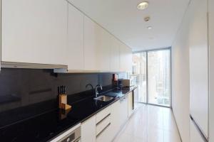 a kitchen with white cabinets and a black counter top at Key View - Emaar Residences, Marina Mall in Dubai