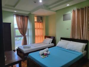 een slaapkamer met 2 bedden en een raam bij Rooms R Us - Voyagers Palace in Puerto Princesa City