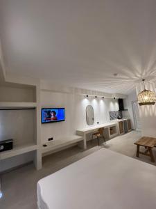 a white bedroom with a bed and a tv at Pefkos Blue in Pefki Rhodes