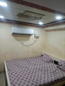 a small bedroom with a bed and a air conditioner at OYO Hotel Yash Galaxy in Kānpur