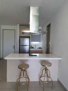 a kitchen with two bar stools and a white counter at Southbay Seaview Condo A10 #10minQueensbay #15minSPICE in Bayan Lepas