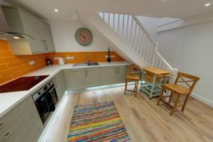 una cocina con fregadero y una escalera con reloj en The Coach House, en Westoe